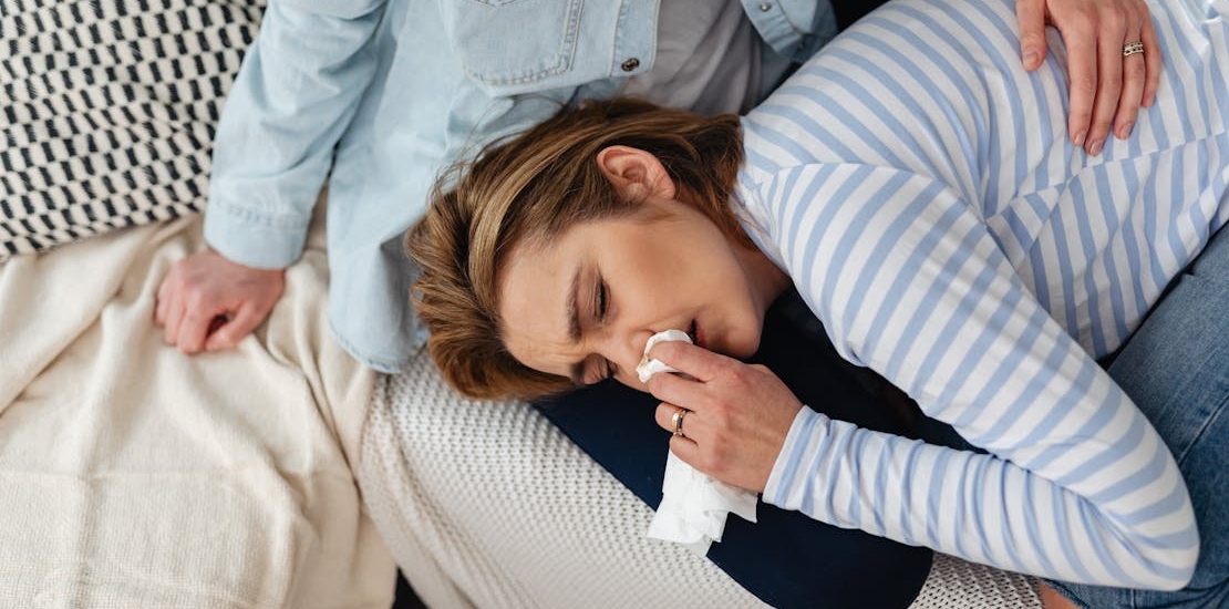 zena lezi u krilu druge osobe i brise nos 