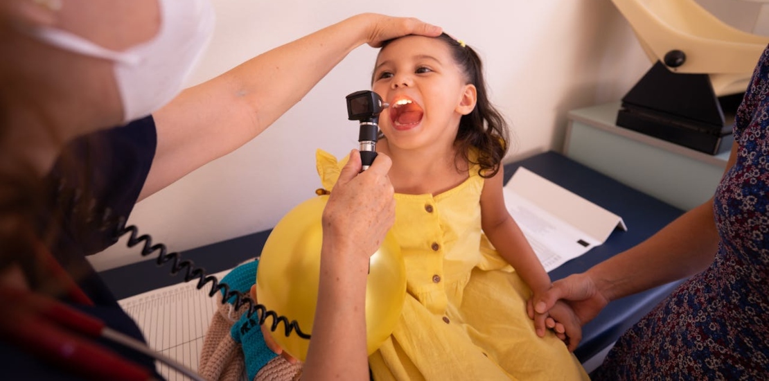 A doctor is examining a young girl’s throat to determine the most common ENT problems in children.