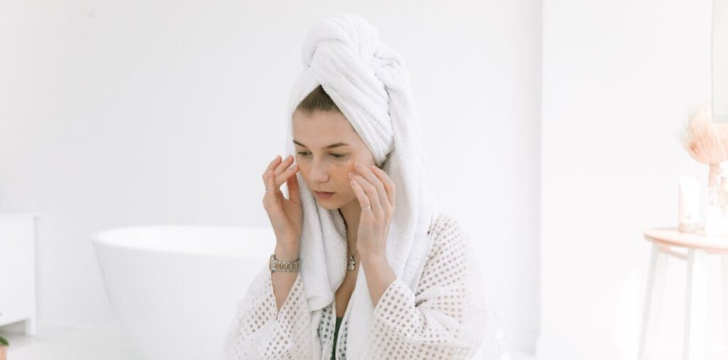 žena se ogleda u ogledalu sa peškirom na glavi 