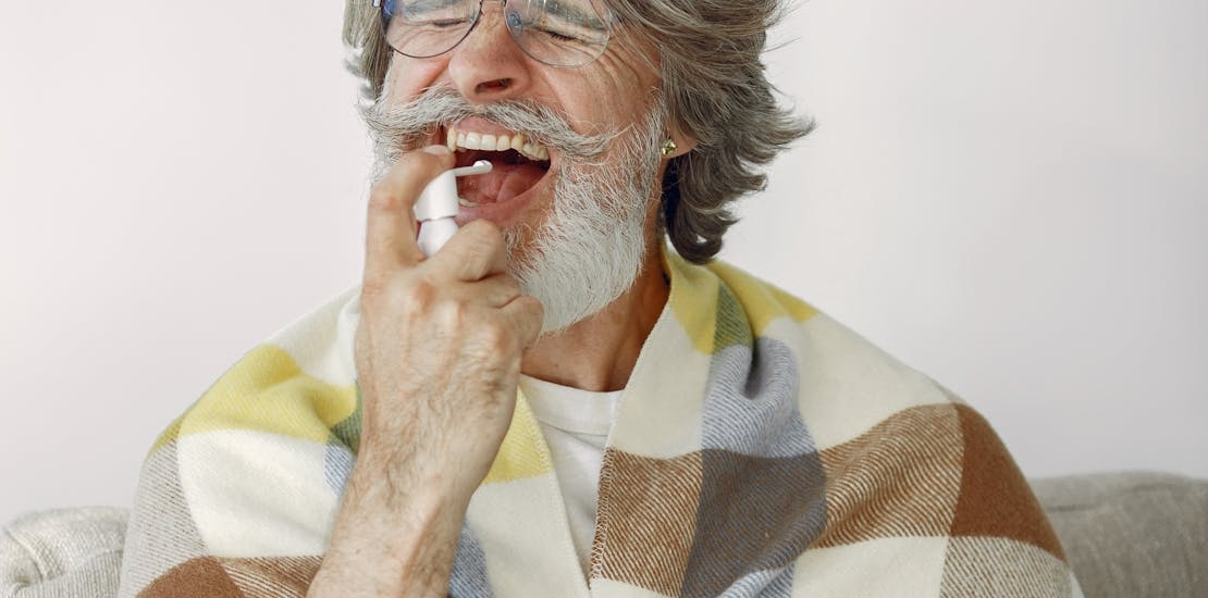 stariji covek koristi sprej za grlo 