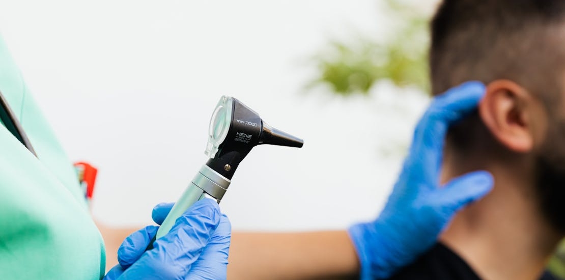 A doctor is examining an ear.
