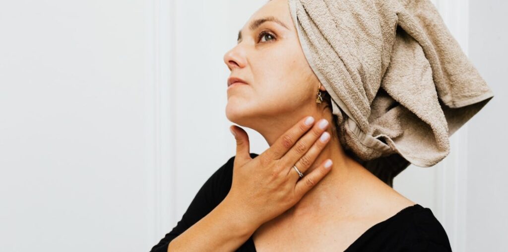 žena sa peškirom na glavi dodiruje vrat