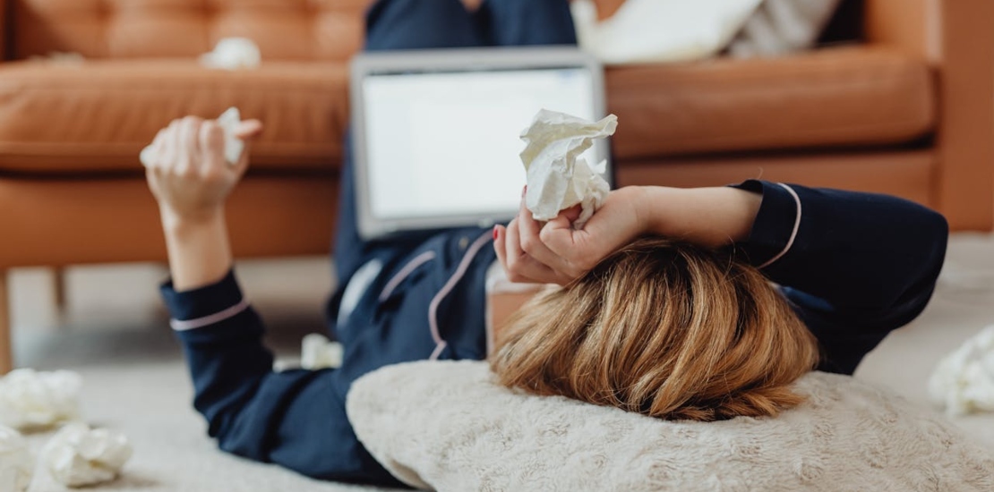 Женщина лежит на полу с бумажными платками в руках.