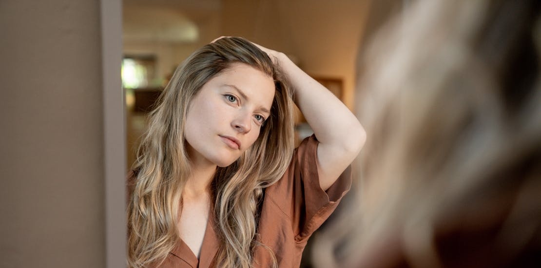 Žena gleda sebe u ogledalu nakon Juvederm Volite tretmana