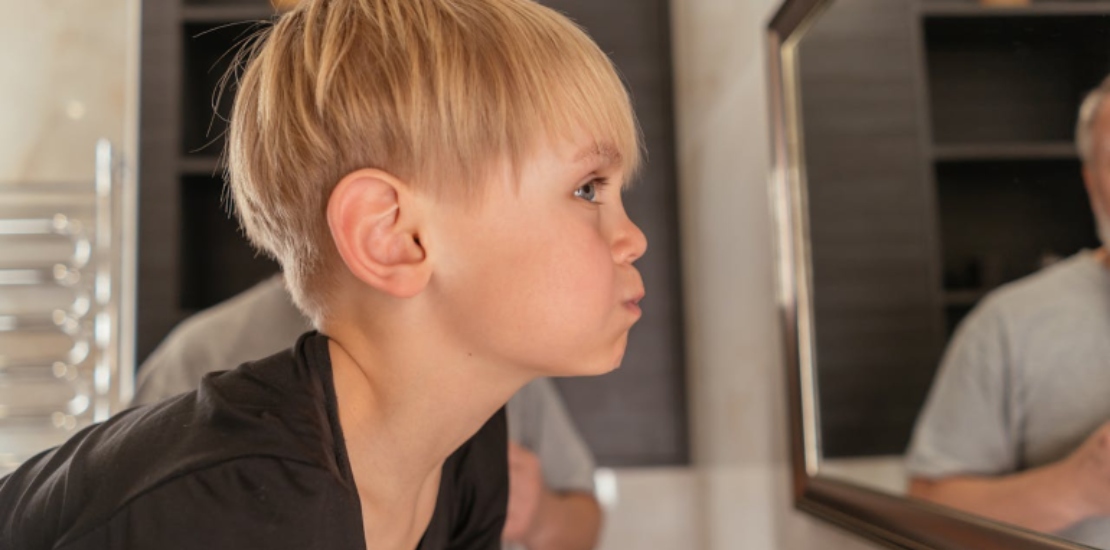 Мальчик полощет рот водой.