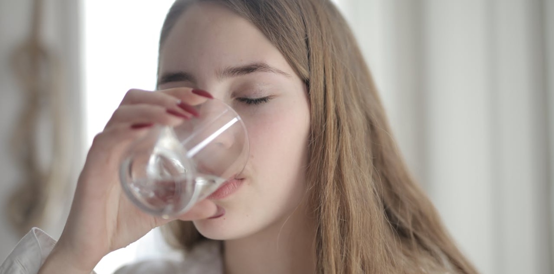 Девушка пьёт солёную воду для горла.