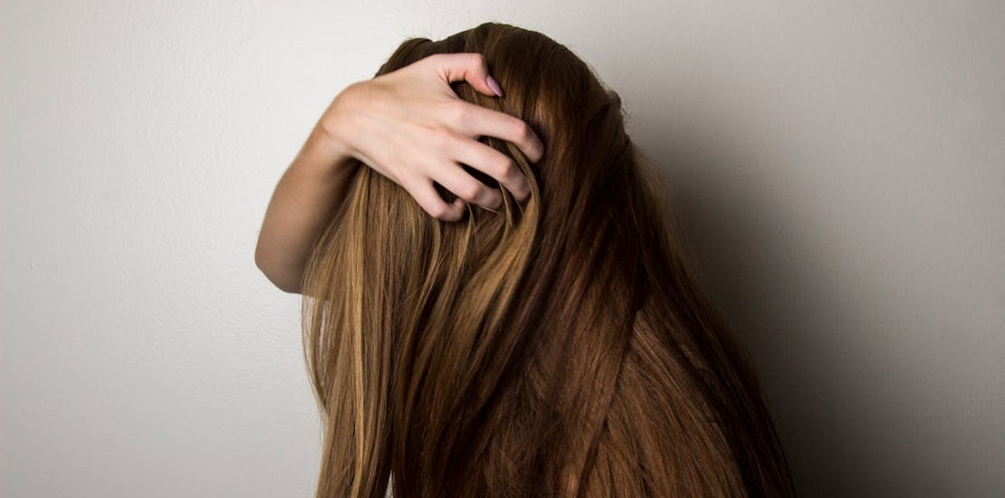Девушка проводит пальцами по волосам.