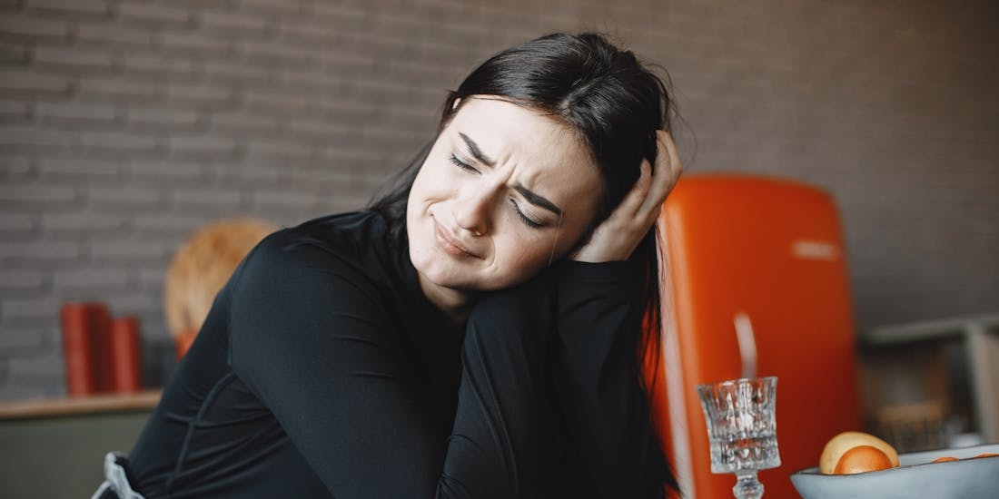 A person holds their hand to their ear in pain - a symptom that may indicate swimmer’s ear