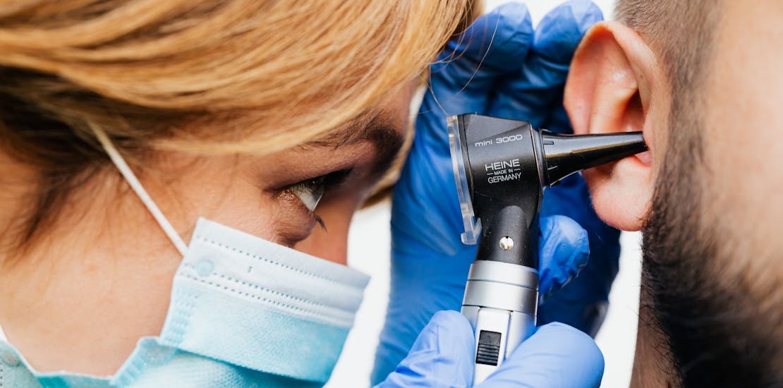 A doctor examines a patient's ear using an otoscope.