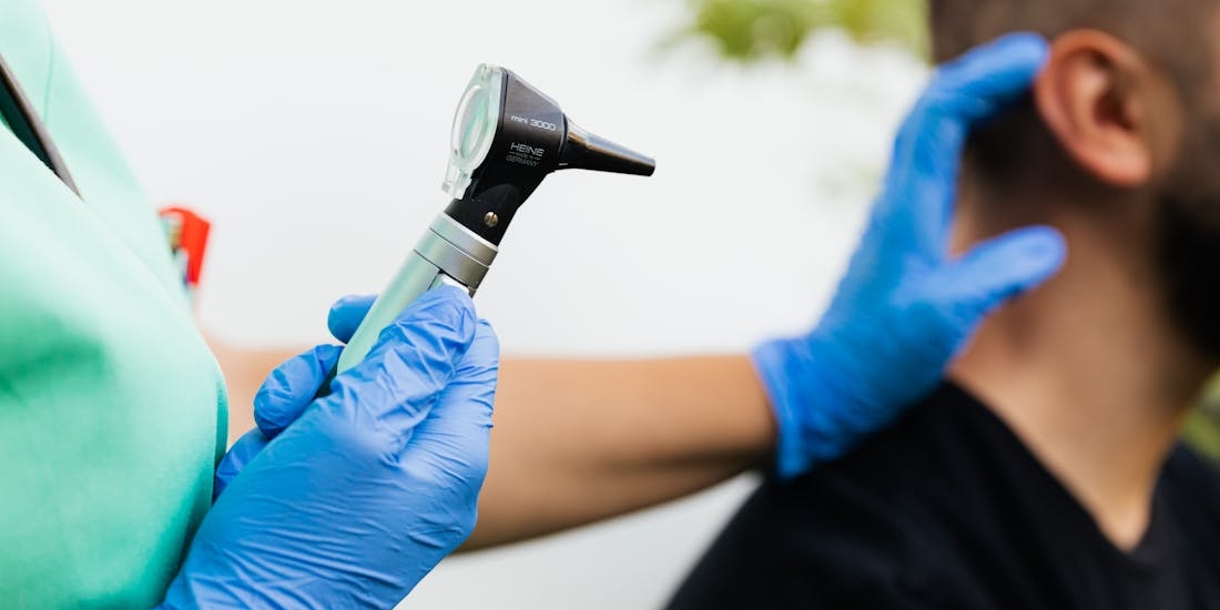 A doctor holds an otoscope and examines a patient’s ear