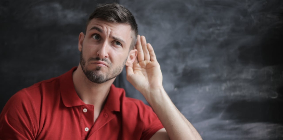 čovek drži ruku na uvu i pokušava nešto da čuje 