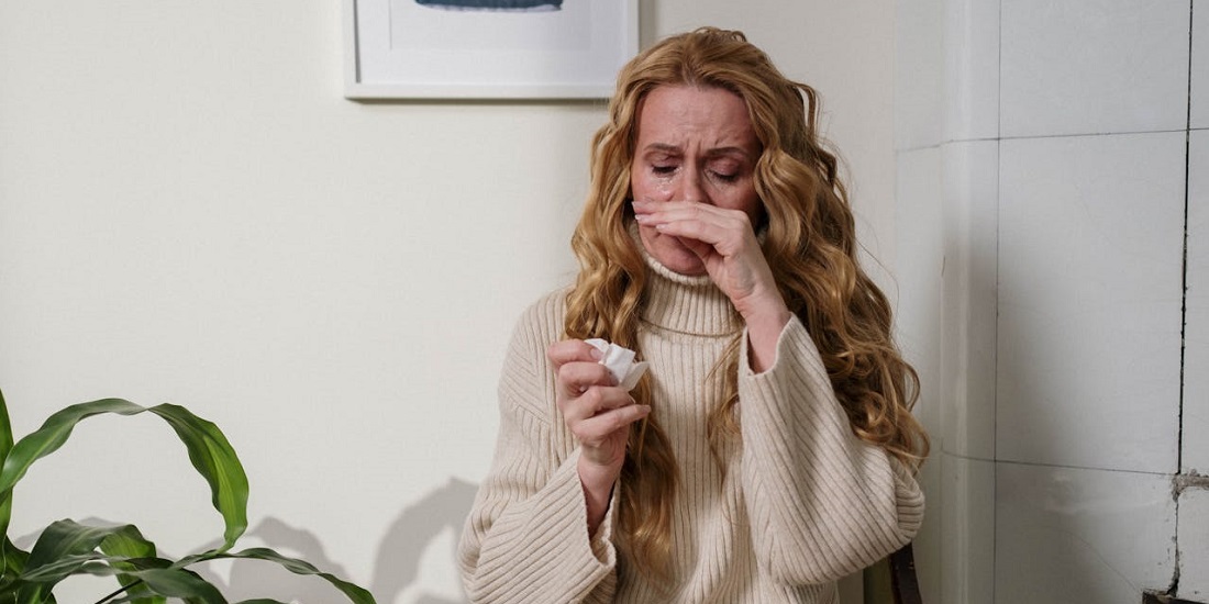 Žena koja ne zna kako koristiti sprej za nos bez štete po sluzokožu, briše nos i izgleda umorno