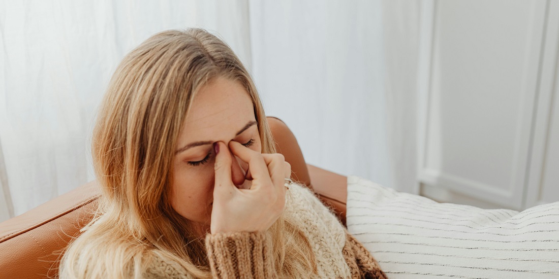 Девушка страдает от головной боли из-за заложенности носа без простуды.