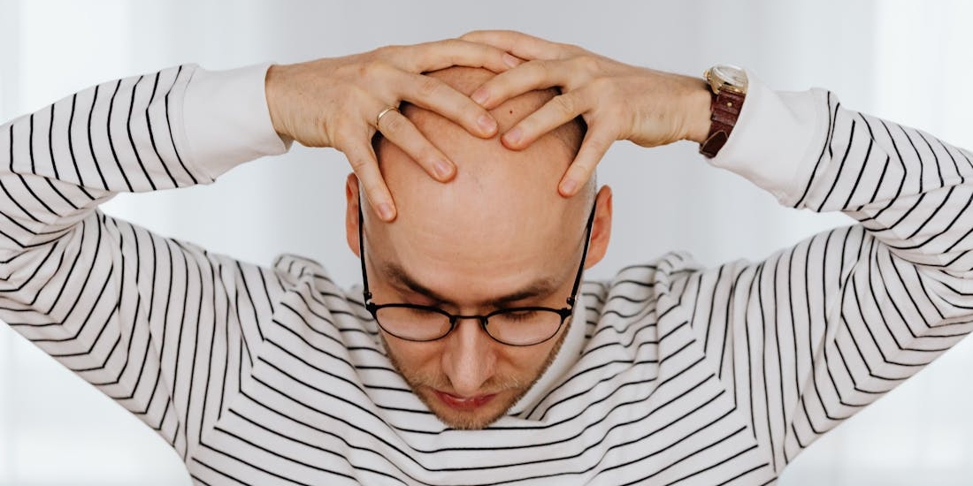 A man holds his head due to dizziness, a possible symptom of labyrinthitis (vestibular neuritis)