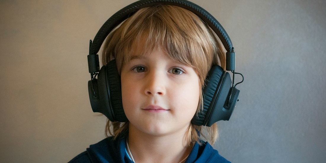 Dete nosi slušalice, gleda u kameru