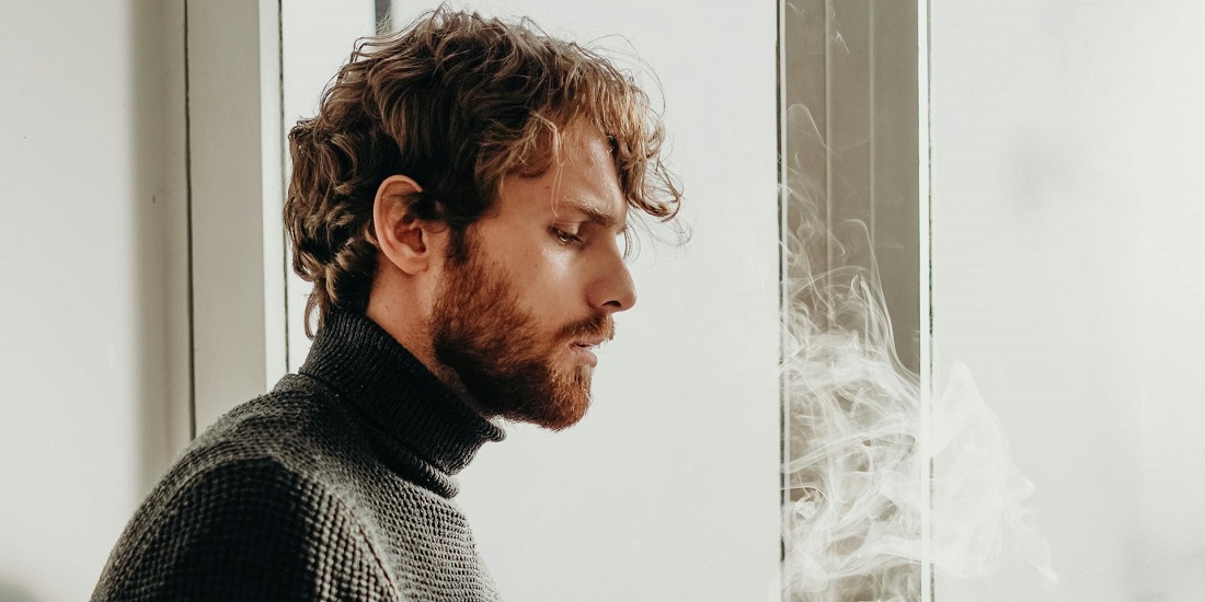 Muškarac puši i razmišlja o posledicama koje duvanski proizvodi imaju na njegovo zdravlje.