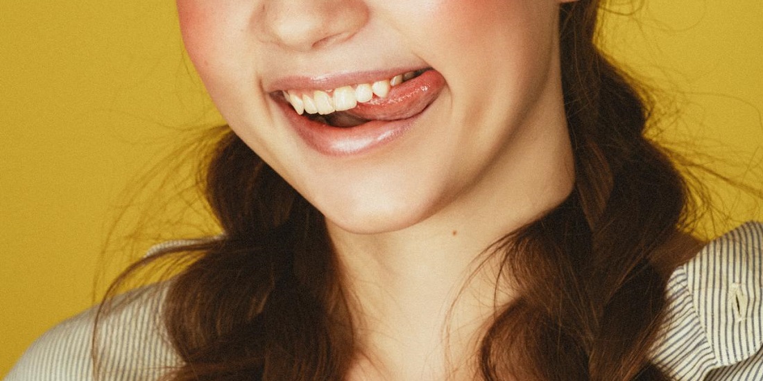 Nasmejana devojka dodiruje jezikom usnu