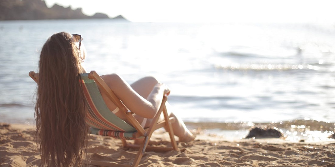Žena se sunča na ležaljci pored mora
