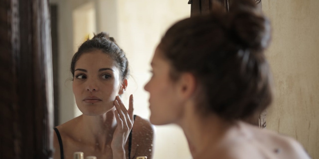 Žena posmatra kožu u ogledalu nakon tretmana