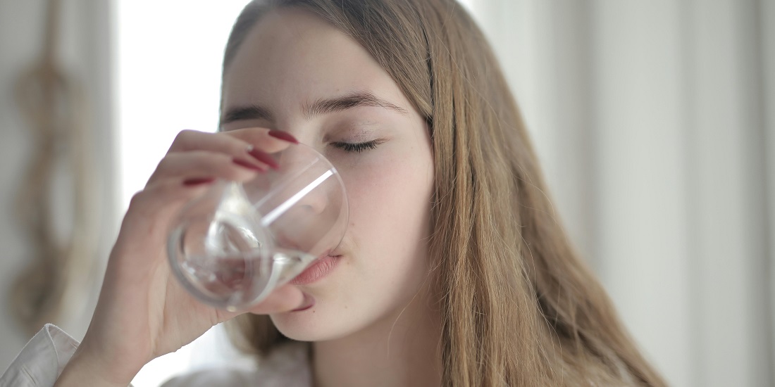 devojka pija vodu jer zna da može vratiti volumen licu nakon naglog mršavljenja uz hidrataciju i pravilnu ishranu 