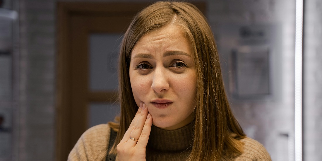 Devojka drži vilicu zbog bola u zubima.