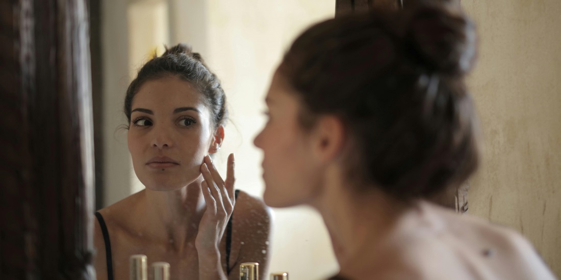 a young woman looking her reflection in the mirror 