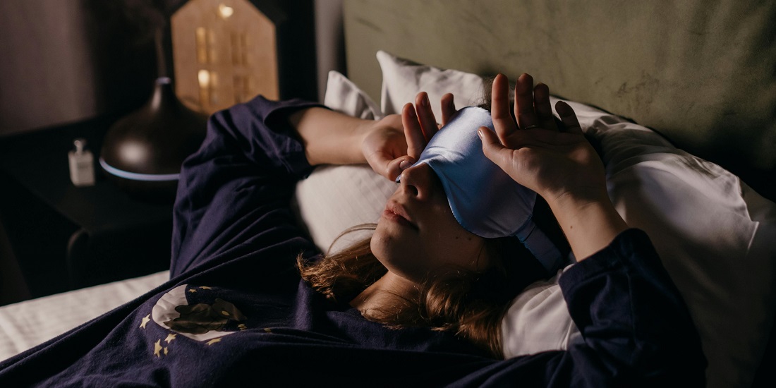 Žena sa maskom za spavanje odmara u krevetu