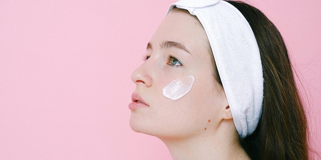 Girl applying cream to her face