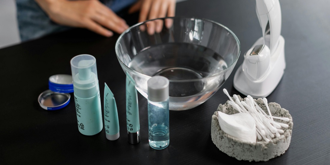 Kozmetički proizvodi i pribor poređani pored činije s vodom