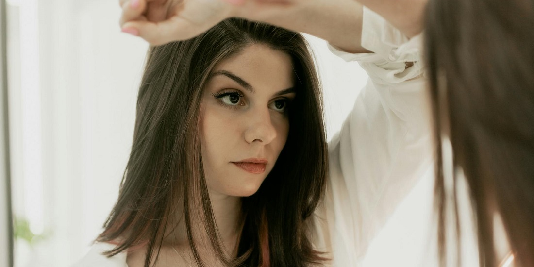 devojka se gleda u ogledalu i pokušava da shvati kako stres poništava rezultate estetskih tretmana