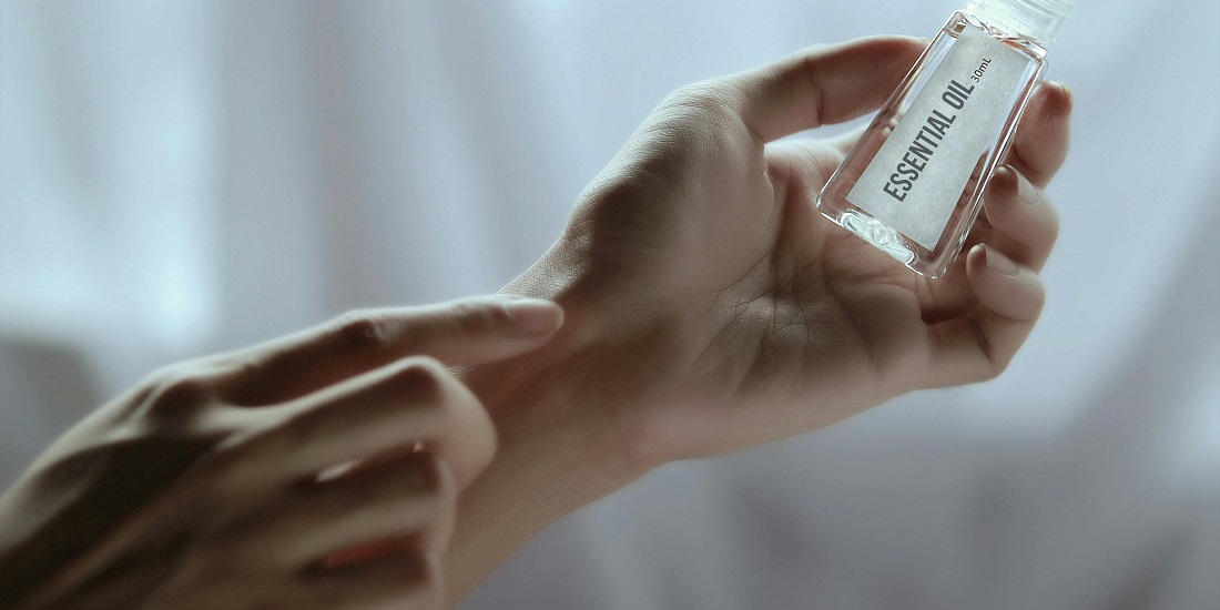The person is applying essential oil to their hand, as they are concerned about the causes of skin peeling.