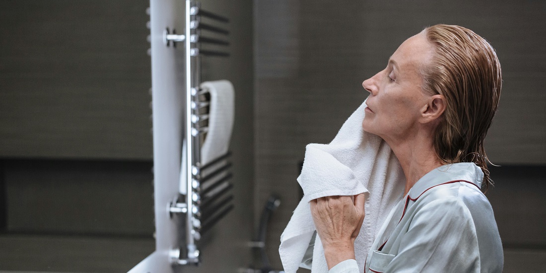 žena nežno briše lice peškirom posle umivanja