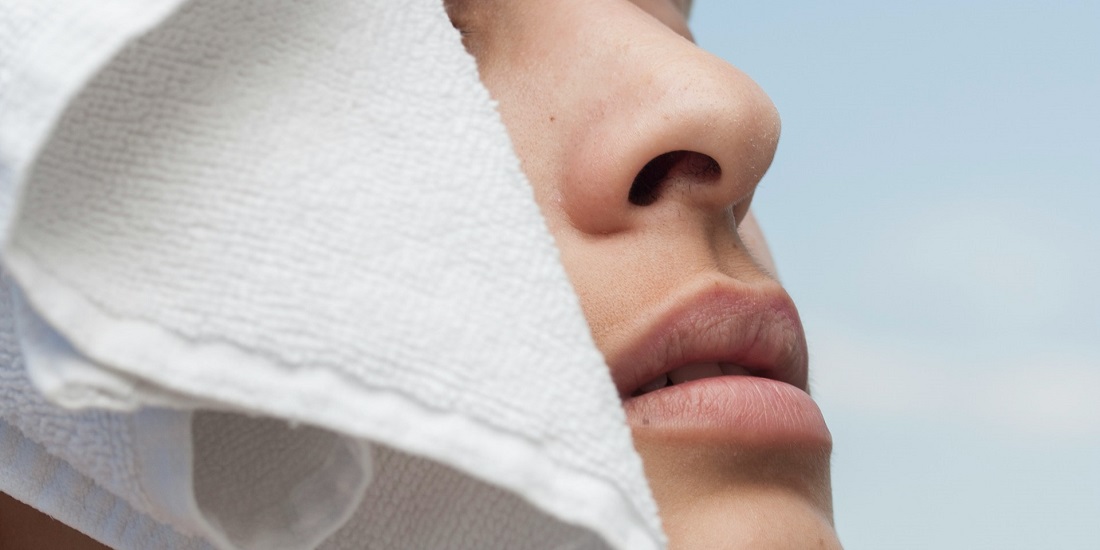 Osoba sa peškirom na licu, verovatno radi sinusne irigacije.