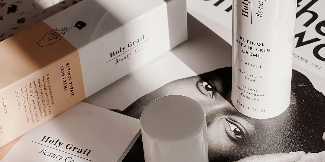 A set of retinol cream and serum on a table with a magazine.