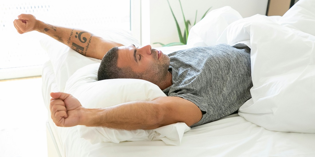 A man wakes up refreshed after practicing breathing techniques.