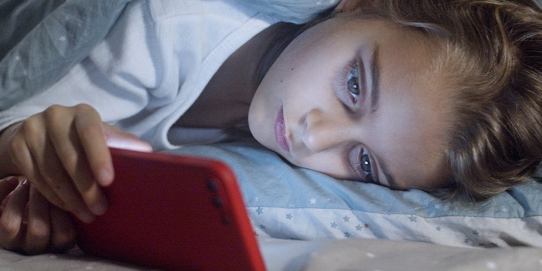 osoba gleda telefon i ne zna koliko zaštita kože od plavog svetla znači