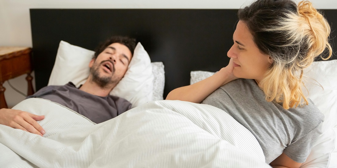 A man snores while his partner watches with concern.