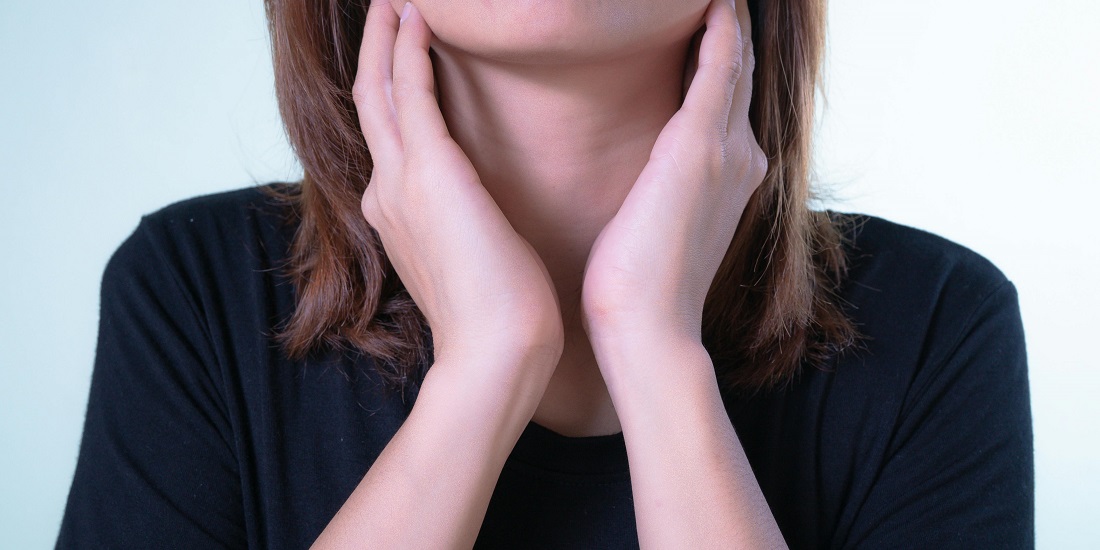 A person holds their neck, trying to understand why does lump in the throat occur with anxiety.