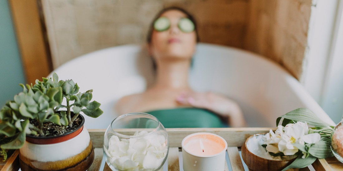 A woman enjoys a relaxing bath with cucumber slices on her eyes.