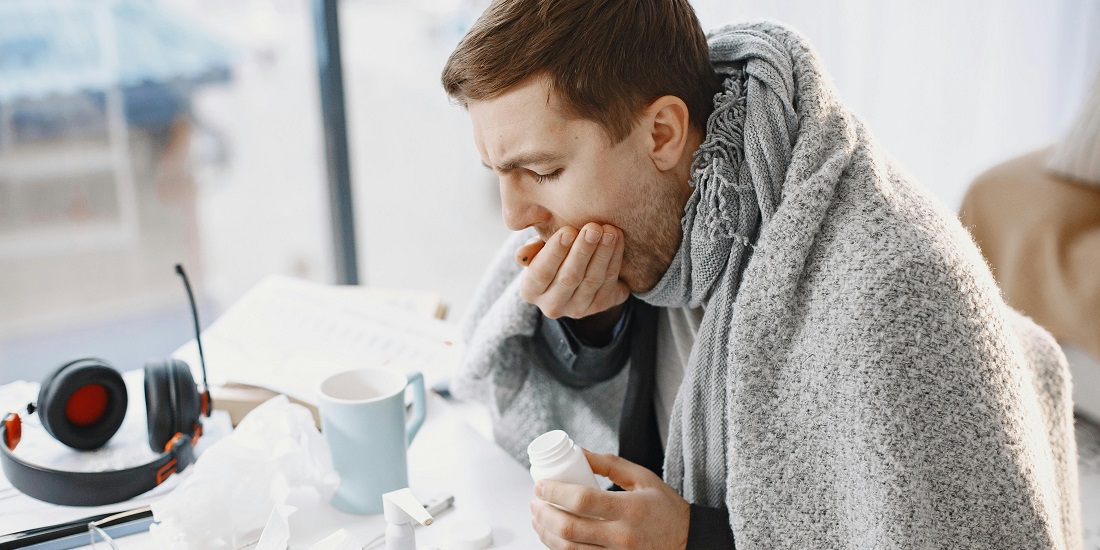 Muškarac sa prehladom sedi sa pokrivačem i razmišlja koji su rizici samostalnog lečenja virusnih infekcija.