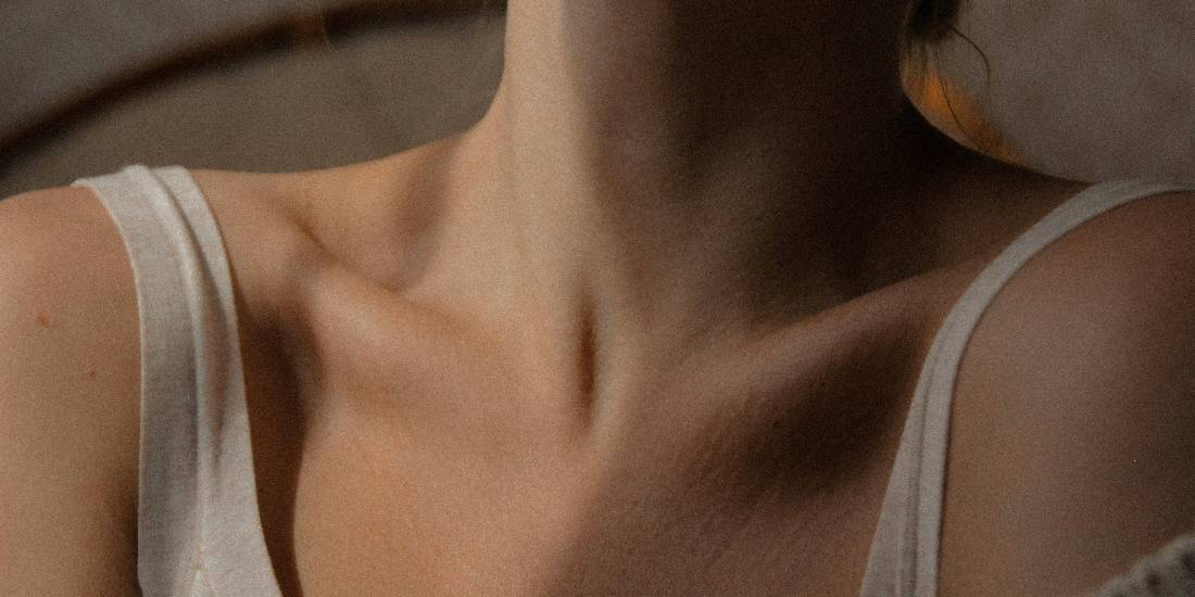 Blizak pogled na vrat žene, sa fokusom na njenu kožu i oblik tela.