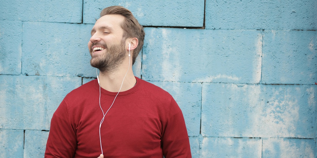 A man listens to music on headphones outside.