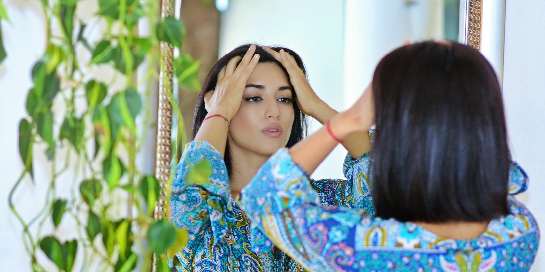 A woman in front of the mirror, facing anxiety about her appearance due to body dysmorphia.