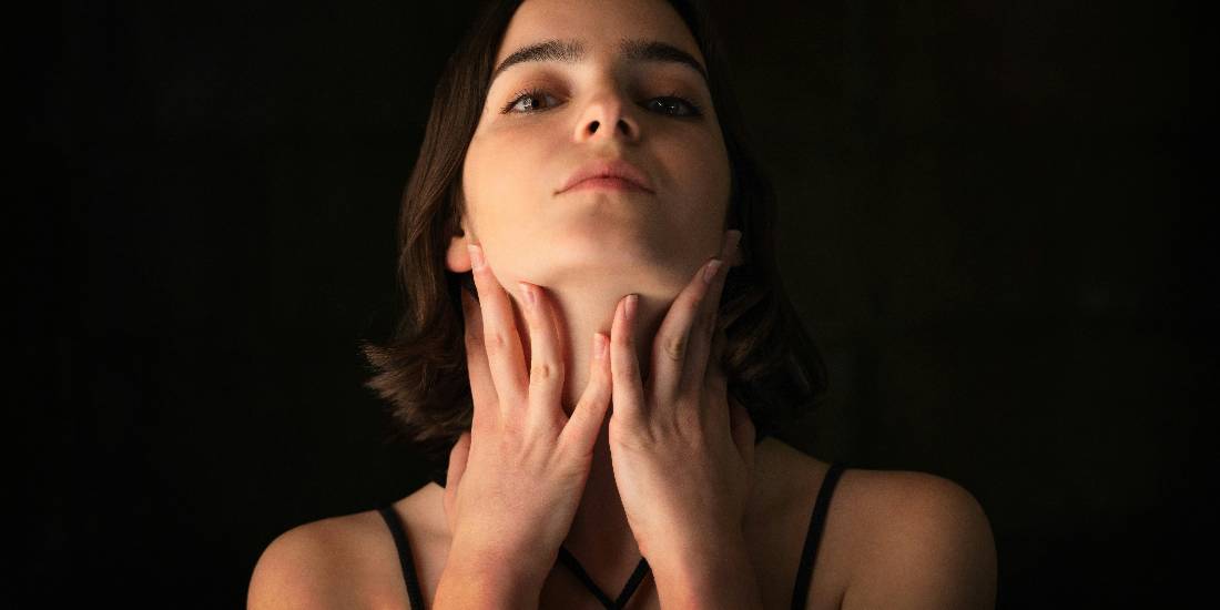 Žena koja podiže glavu, sa dodirom vrata, što može ukazivati na promene koje se odnose na razvoj raka grla.