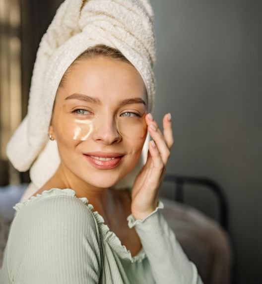 žena se smeši sa peškirom na glavi i jastučićima preko podočnjaka