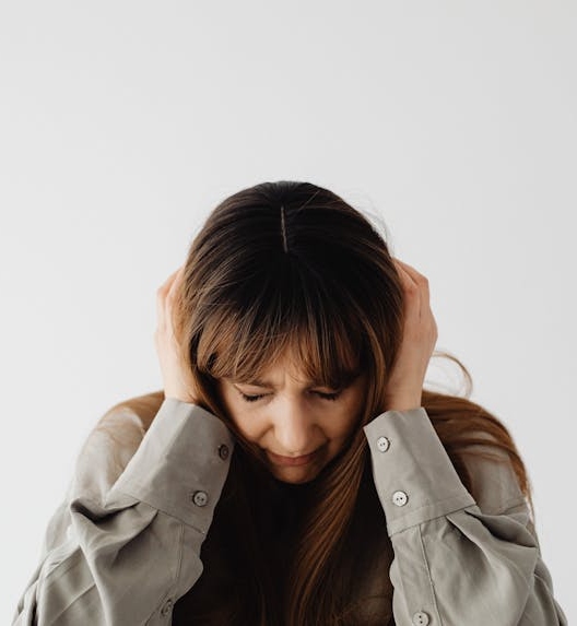 A woman with her head down is experiencing intense ear pressure.