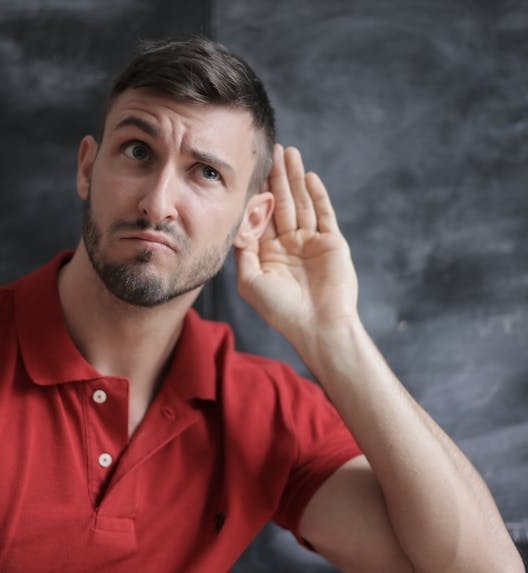 A person is trying to hear better, which may indicate hearing loss