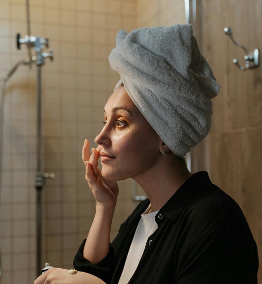 Žena nežno nanosi kremu na lice