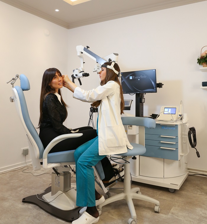 Lekarka obavlja mikroskopski pregled uha kod pacijentkinje