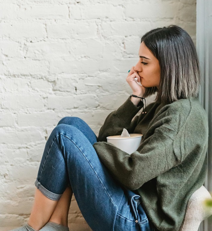 Mlada žena sedi zamišljena držeći kutiju maramica.